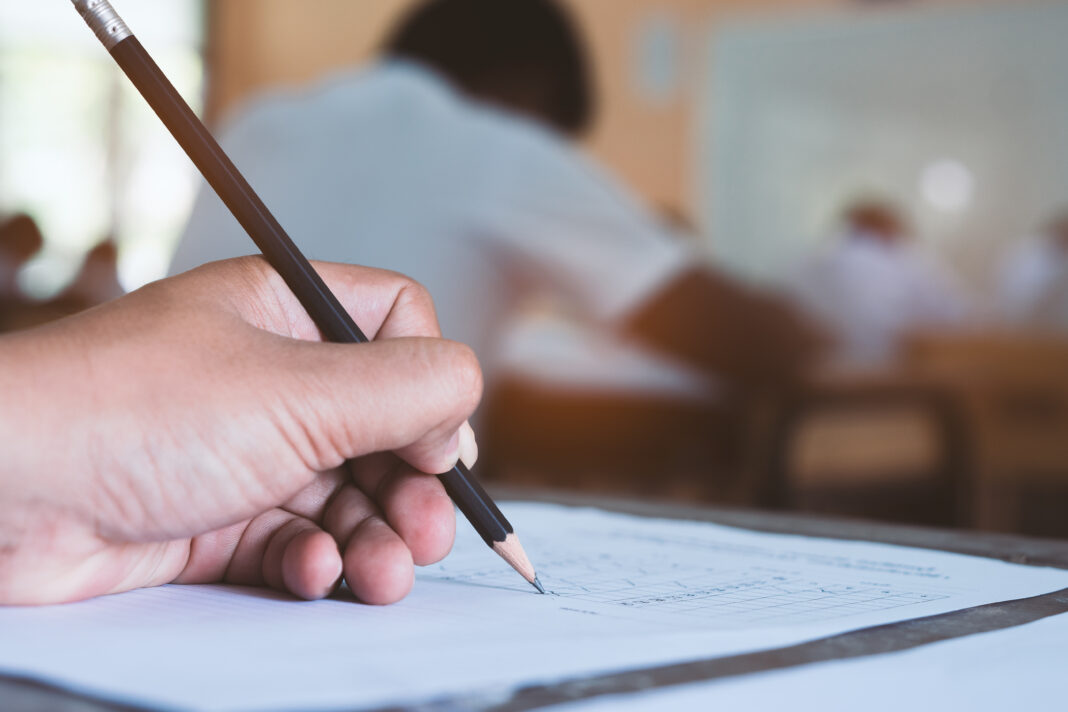 Close up to hand of student  holding pen and taking exam in clas