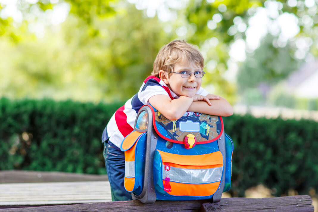 little kid boy with school satchel on first day to school