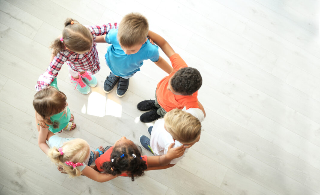 Little children making circle with hands around each other indoo