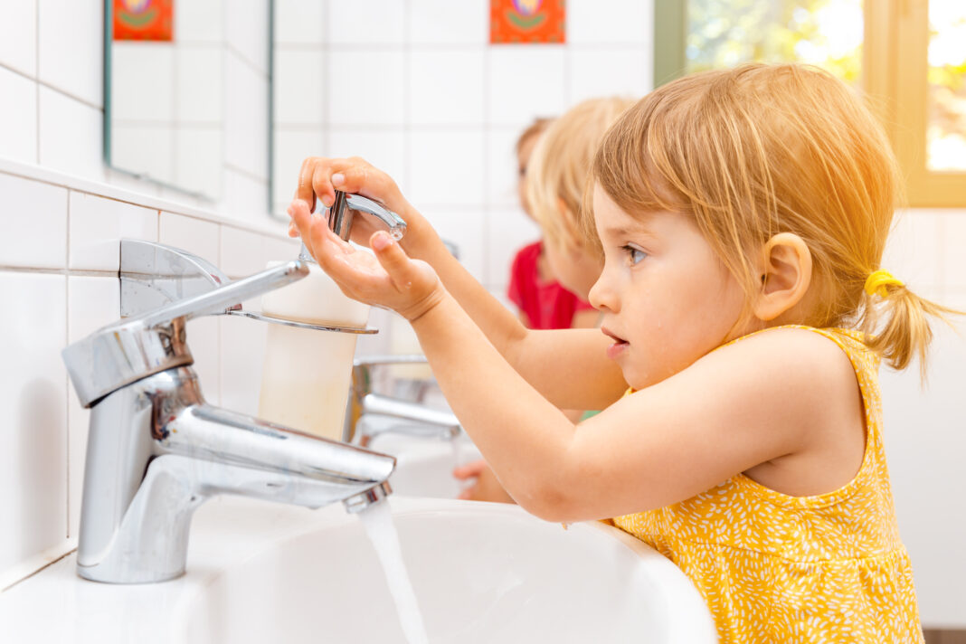 Child in kindergarten washing her hands