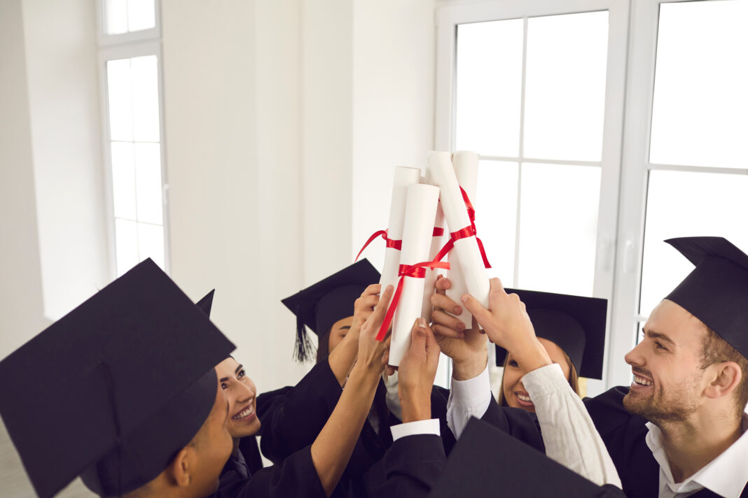 Smiling university students in traditional black hats celebrating successful graduation