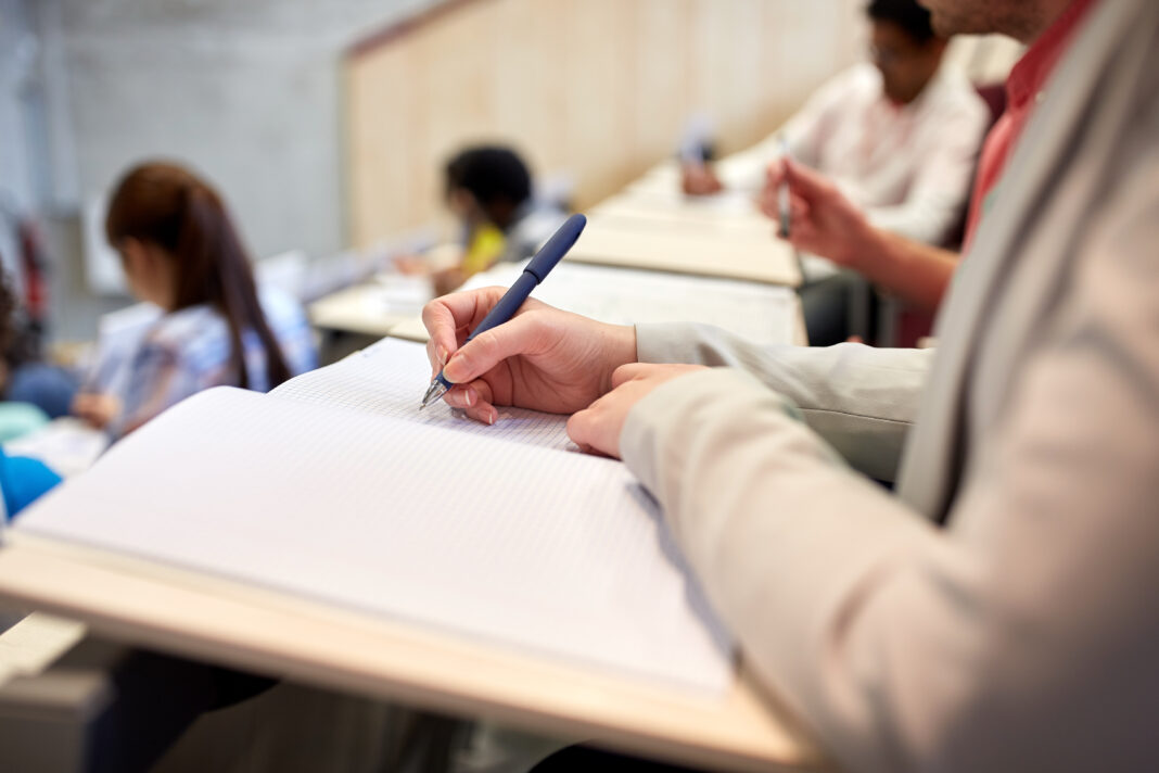 student writing to notebook at exam or lecture