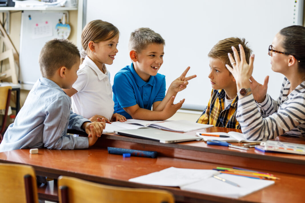 A kind female teacher spends time with her elementary school students, making learning enjoyable and fun while sparking curiosity and fostering a love for education.