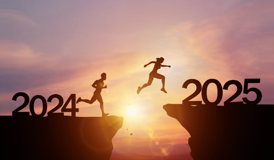 New Year 2025, Inspiration and progress towards new success. Silhouettes of human jumping over cliff towards finish line with text new year 2025 on sunset beautiful