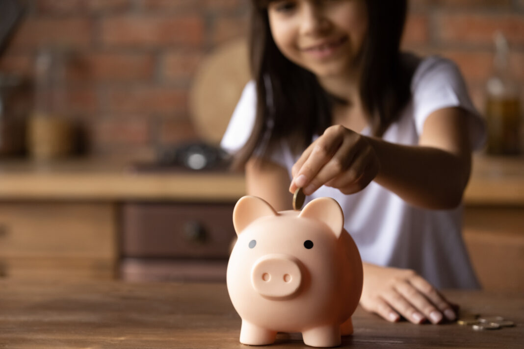 Close up of little girl save money in piggybank