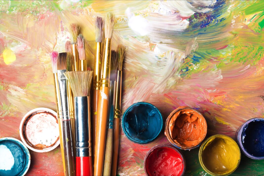 Artist paint brushes and paint cans of paint over bright waterco